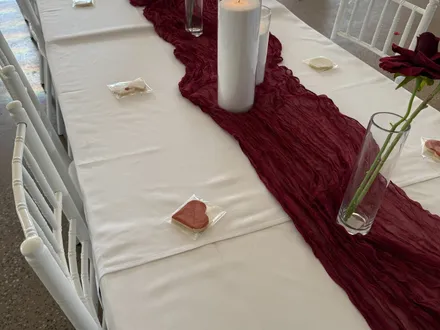 Reception table with a burgundy runner, candles and red roses at The Orchard Penrith