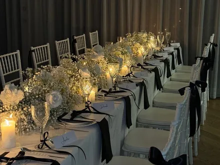 Candlelit long table with baby's breath and black ribbon chair sashes at The Orchard Penrith