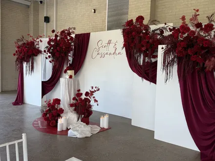 Wedding backdrop with deep red florals and drapes in the Pavilion at The Orchard Penrith