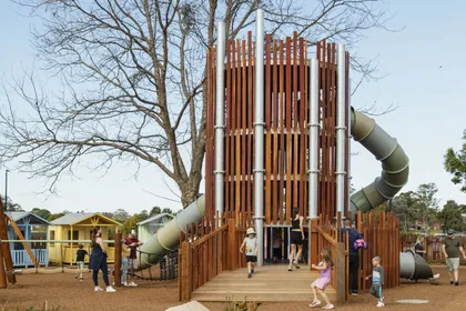 Fenced playground with kids playing and parents nearby